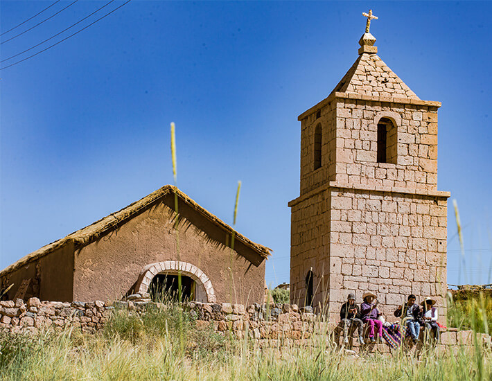 Stone church and locals sitting on the wall